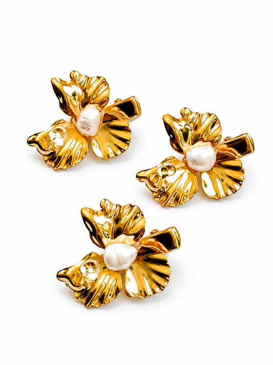Three gold flower-shaped earrings with white pearl centers, arranged on a plain white background.