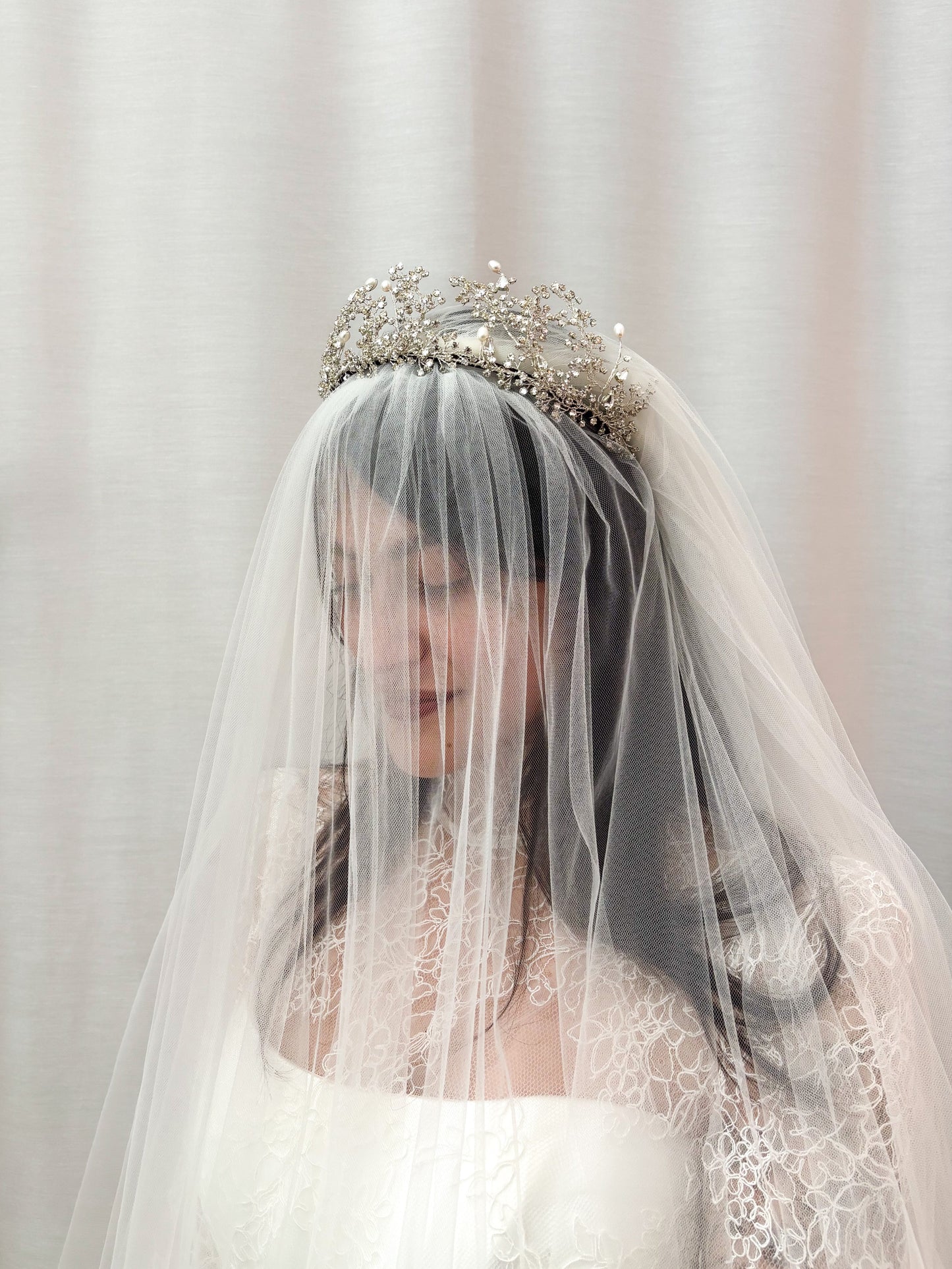 Woman wearing a Wuthering Heights Tiara and wedding dress with a veil and tiara against a plain background
