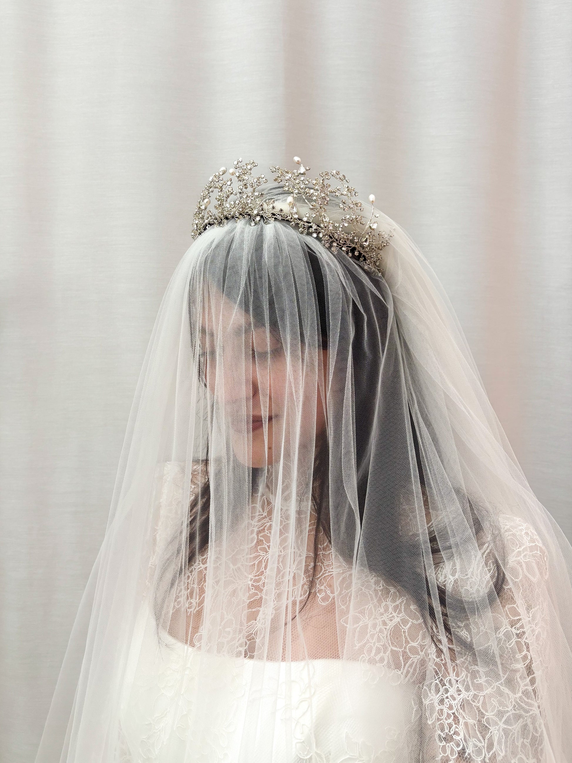 Woman wearing a Wuthering Heights Tiara and wedding dress with a veil and tiara against a plain background