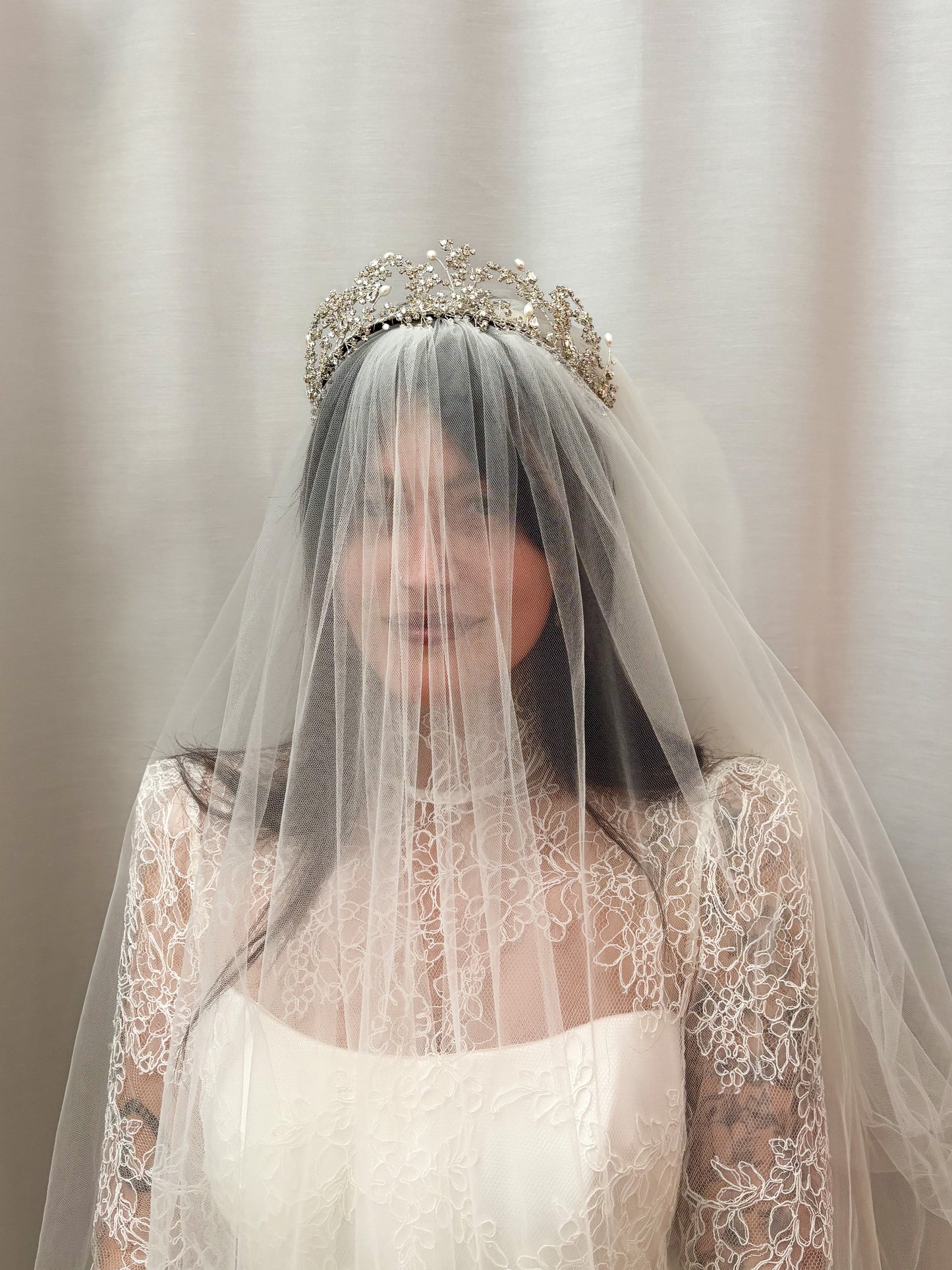 Bride wearing a Wuthering Heights crystal tiara and veil against a neutral background